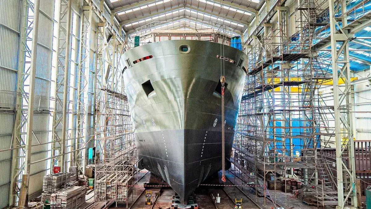 Casco de un buque en construcción rodeado de andamios en la nave de un astillero