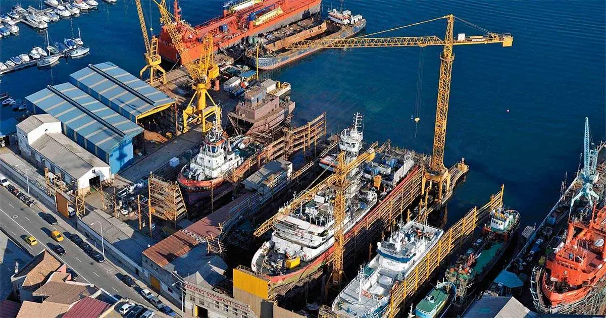 Vista aérea de un astillero con buques en reparación y grúas de puerto